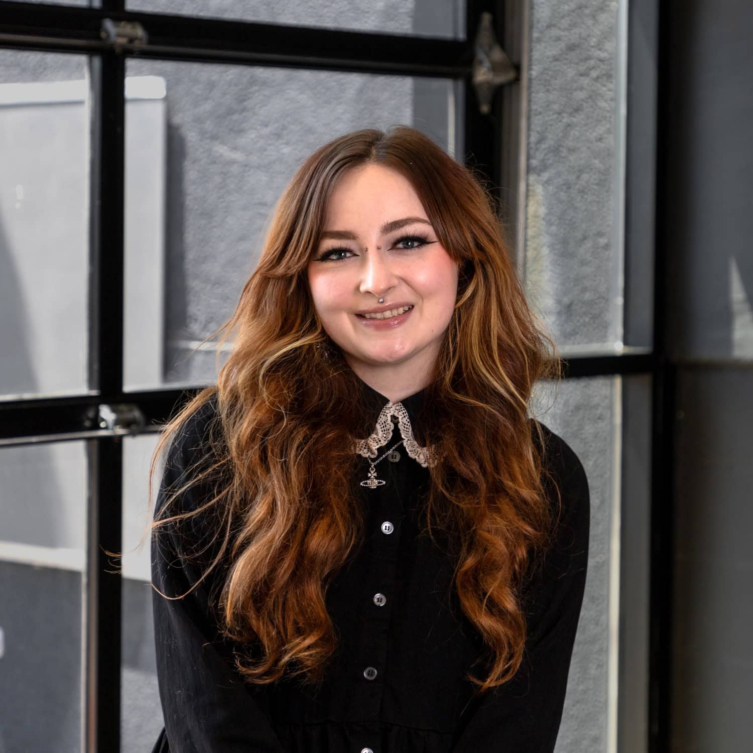 Portrait of a smiling woman with long wavy hair in an office setting.