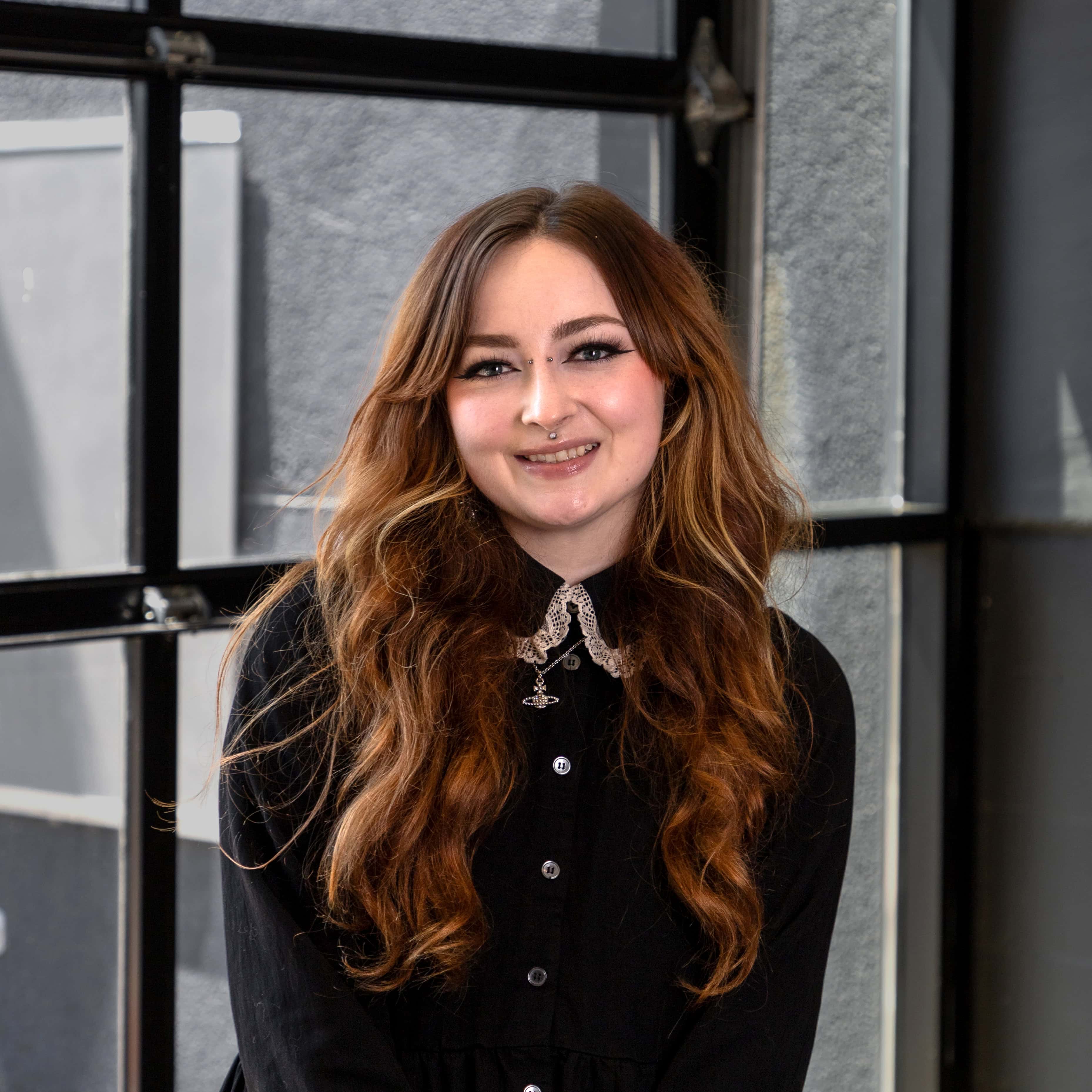 Portrait of a smiling woman with long wavy hair in an office setting.